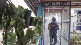 Penumpang melewati bilik disinfektan untuk masuk ke Halte Transjakarta Harmoni, Jakarta, Rabu (8/4). [Suara.com/Alfian Winanto]