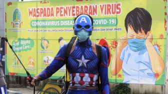 Petugas kepolisian berpakaian superhero menyemprotkan cairan disinfektan di Jalan Panglima Sudirman kawasan Kebonagung, Pasuruan, Jawa Timur, Kamis (9/4). [ANTARA FOTO/Umarul Faruq]