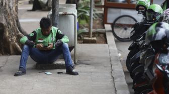 Pengendara ojek online menunggu pesanan di kawasan Pejaten, Jakarta, Jumat (10/4). [Suara.com/Angga Budhiyanto] 