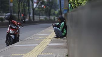 Pengendara ojek online menunggu pesanan di kawasan Pejaten, Jakarta, Jumat (10/4). [Suara.com/Angga Budhiyanto] 