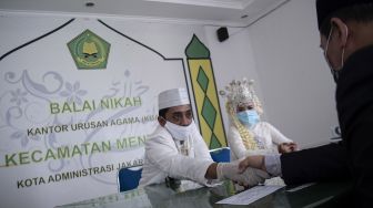 Pasangan pengantin Novi Herdjanto (kiri) dan Mellawati Isnoer melangsungkan prosesi akad nikah di Kantor Urusan Agama Kecamatan Menteng, Jakarta Pusat, Sabtu (11/4). [ANTARA FOTO/Sigid Kurniawan]