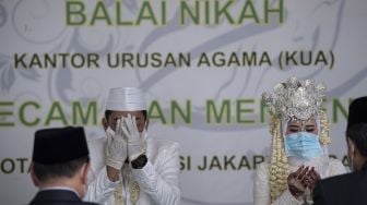 Pasangan pengantin Novi Herdjanto (kedua kiri) dan Mellawati Isnoer memanjatkan doa dalam prosesi akad nikah di Kantor Urusan Agama Kecamatan Menteng, Jakarta Pusat, Sabtu (11/4). [ANTARA FOTO/Sigid Kurniawan]