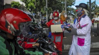 Anggota Perkumpulan Badut Jawa Barat (PBJB) membagikan masker di Pasteur, Bandung, Jawa Barat, Sabtu (11/4). [ANTARA FOTO/Raisan Al Farisi]