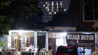 Warga Rawa Bambu beraktivitas di rumahnya dengan latar belakang lampu hotel berbentuk lafaz Allah di Jakarta Selatan, Minggu (12/4).   [Antara Foto]