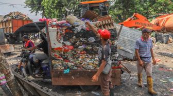 Petugas memasukan sampah ke mobil sampah  di TPS Kalibata, Jakarta Selatan, Senin (13/4). [Suara.com/Alfian Winanto]
