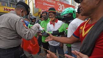 Anggota polisi mambagikan nasi bungkus kepada buruh, pedagang kaki lima dan pengemudi ojek saat membuka dapur umum di Alun-alun Serang, Banten, Selasa (14/4).   [ANTARA FOTO/Asep Fathulrahman]
