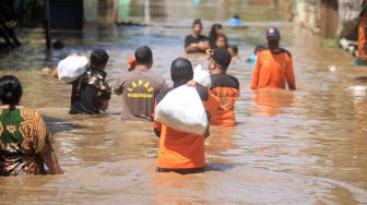 Relawan mambawa makanan untuk di bagikan kepada korban banjir yang menggenangi kawasan Kraton, Pasuruan, Jawa Timur, Selasa (14/4). [ANTARA FOTO/Umarul Faruq]