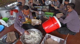 Sejumlah personel Polda Banten membungkus nasi dan sayur mayur saat membuka dapur umum di Alun-alun Serang, Banten, Selasa (14/4).  [ANTARA FOTO/Asep Fathulrahman]