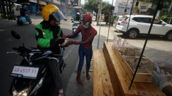 Spiderman membagikan nasi bungkus di depan Hotel Dafam, Seturan, Sleman, D.I Yogyakarta, Rabu (15/4).  [ANTARA FOTO/Andreas Fitri Atmoko]