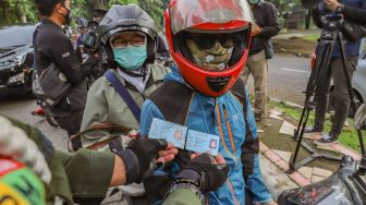 Petugas mencocokan KTP pengendara yang berboncengan saat Pemberlakuan PSBB di Check Point PSBB Kota Depok dibawah Flyover UI, Lenteng Agung, Jakarta Selatan, Rabu (15/4). [Suara.com/Alfian Winanto]