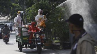 Petugas Palang Merah Indonesia (PMI) diatas motor menyemprotkan cairan disinfektan di lingkungan asrama Sekolah Tinggi Teknologi (STT) Bethel di kawasan Petamburan, Jakarta, Jumat (17/4).  [Suara.com/Angga Budhiyanto]
