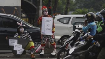 Badut yang tergabung dalam Aku Badut Indonesia (ABI) melakukan kampanye melawan virus Corona di kawasan Pasar Rebo, Jakarta, Sabtu (18/4). [Suara.com/Angga Budhiyanto]