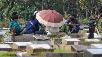 Warga berdoa di makam kerabatnya di Tempat Pemakaman Umum (TPU) Karet Bivak, Jakarta Pusat, Minggu (19/4). [Suara.com/Alfian Winanto]