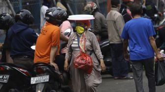 Pedagang membawa barang dagangannya melintas di kawasan Pasar Minggu, Jakarta, Selasa (21/4). [Suara.com/Angga Budhiyanto]











