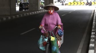 Pedagang membawa barang dagangannya dengan sepeda melintas di kawasan Kebayoran Baru, Jakarta, Selasa (21/4). [Suara.com/Angga Budhiyanto]











