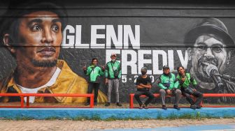 Warga berfoto di depan mural Glenn Fredly di Lapangan Basket Panglima Polim, Jakarta Selatan, Selasa (21/4). [Suara.com/Alfian Winanto]