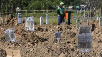 Penjaga makam melintas di pusara kasus meninggal akibat virus Corona COVID-19 sebagai pengganti nisan di komplek TPU Tegal Alur, Jakarta, Rabu (22/4).  [ANTARA FOTO/Muhammad Adimaja]
