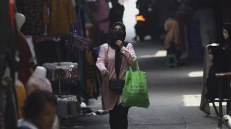 Warga melintas di pasar Tanah Abang yang sepi pengunjung pada hari kedua di bulan suci Ramadhan akibat pandemi virus Corona (COVID-19) di Jakarta, Minggu (26/4). [Suara.com/Angga Budhiyanto]