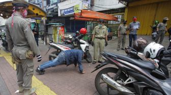 Pengendara motor menjalani hukuman push up dikarenakan tidak memakai masker saat razia Pembatasan Sosial Berskala Besar(PSBB) di Kawasan Jalan Fatmawati, Jakarta, Selasa (28/4).  [ANTARA FOTO/Reno Esnir]