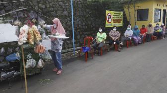 Antrean untuk membeli sayur dengan menjaga jarak di Perumahan Taman Anyelir 3, Cilodong, Depok, Jawa Barat, Selasa (28/4).  [Suara.com/Angga Budhiyanto]