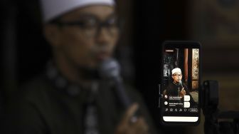 Seorang ustaz tadarus Al-Quran secara online di Masjid Agung Sunda Kelapa, Jakarta, Selasa (28/4). [Suara.com/Angga Budhiyanto]
