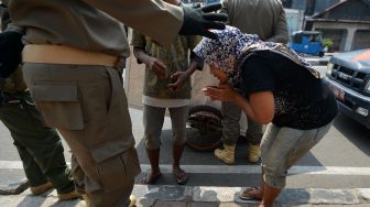 Pengemis memohon untuk tidak ditangkap petugas Satpol PP di Jalan Dewi Sartika, Cawang, Jakarta, Rabu (29/4). [ANTARA FOTO/Aditya Pradana Putra]