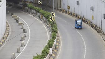 Bajaj melintas di samping underpass Senen yang ditutup di Jakarta, Jumat (1/5).  [Suara.com/Angga Budhiyanto]