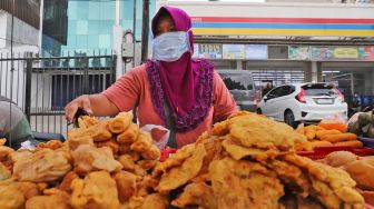 Pedagang merapikan gorengan jualannya di Jalan Panjang, Kebon Jeruk, Jakarta barat, Jumat (1/5). [Suara.com/Alfian Winanto]