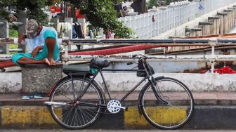 Pengojek sepeda ontel berteduh di bawah pohon menunggu penumpang di kawasan Kota Tua, Jakarta Barat, Minggu (3/5). [Suara.com/Alfian Winanto]