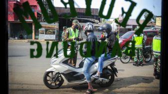 Petugas memberhentikan kendaraan bermotor di titik pemeriksaan Pembatasan Sosial Berskala Besar (PSBB) di Jatinangor, perbatasan Kabupaten Bandung dan Kabupaten Sumedang, Jawa Barat, Rabu (6/5).  [ANTARA FOTO/Raisan Al Farisi]
