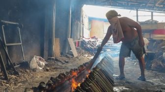 Pekerja melihat keadaan bara api untuk membakar lemang di Kramat Raya, Senen, Jakarta Pusat, Rabu (6/5). [Suara.com/Alfian Winanto]