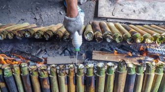 Pekerja memasukan santan kedalam lemang di Kramat Raya, Senen, Jakarta Pusat, Rabu (6/5). [Suara.com/Alfian Winanto]