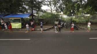 Sejumlah warga mengantre dengan menerapkan aturan jarak fisik atau 'physical distancing' untuk mendapatkan takjil gratis di Jalan Cempaka Putih Tengah, Kecamatan Cempaka Putih, Jakarta Pusat, Kamis (7/5). [Suara.com/Angga Budhiyanto]