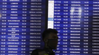 Petugas berada di depan papan informasi keberangkatan di Terminal 3 Bandara Soekarno Hatta, Tangerang, Banten, Kamis (7/5). [Suara.com/Angga Budhiyanto]