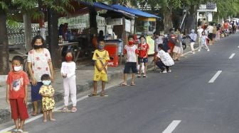 Warga mengantre dengan menerapkan aturan jarak fisik atau 'physical distancing' untuk mendapatkan takjil gratis di Jalan Cempaka Putih Tengah, Kecamatan Cempaka Putih, Jakarta Pusat, Kamis (7/5). [Suara.com/Angga Budhiyanto]