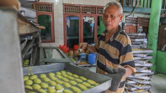 Pekerja memasukan kue kering kedalam oven untuk dimasak di toko kue Pusaka Kwitang, Jakarta Pusat, Kamis (7/5). [Suara.com/Alfian Winanto]