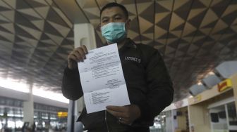 Seorang calon penumpang dengan ijin khusus kembali ke daerah asal usai menjalani pendidikan di Arab Saudi menunjukan surat syarat terbang di Terminal 3 Bandara Soekarno Hatta, Tangerang, Banten, Kamis (7/5).  [Suara.com/Angga Budhiyanto]