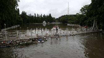 Warga melintas di jembatan di kawasan wisata sejarah Putroe Phang yang tergenang banjir di Banda Aceh, Aceh, Sabtu (9/5). [ANTARA FOTO/Irwanyah Putra]