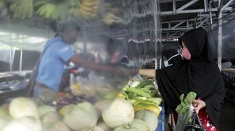 Pembeli berbelanja dengan sekat tirai pelindung plastik pada kios jualan di Pasar Kaget Borong Indah, Makassar, Sulawesi Selatan, Sabtu (9/5). [ANTARA FOTO/Arnas Padda]