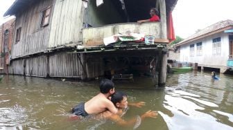 Orang tua mengajarkan anaknya berenang saat banjir luapan Sungai Batanghari merendam kawasan permukiman di Mudung Laut, Pelayangan, Jambi, Jumat [ANTARA FOTO/Wahdi Septiawan]