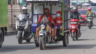 Pengendara sepeda motor membawa penumpang di kawasan Kramat Jati, Jakarta Timur, Rabu (13/5). [Suara.com/Alfian Winanto]