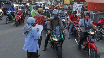 Petugas mengecek suhu tubuh pengendara sepeda motor yang akan memasuki Bekasi dengan Thermo Gun di Check Point PSBB Pondok Gede, Bekasi, Jawa Barat, Kamis (15/5). [Suara.com/Alfian Winanto]