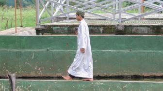 Seorang santri berjalan di tepi kolam di Pesantren Al - Kautsar Darul Quran, Bogor, Jawa Barat, Rabu (13/5). [Suara.com/Alfian Winanto]