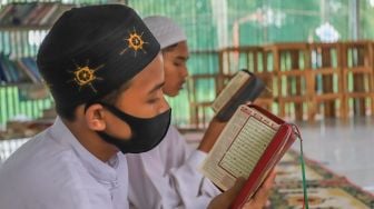 Dua orang santri membaca Al Quran dengan khusyuk di Pesantren Al Kautsar Darul Quran, Bogor, Jawa Barat, Rabu (13/5). [Suara.com/Alfian Winanto]