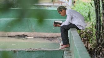 Santri menghafal Al Quran di tepi kolam di Pesantren Al Kautsar Darul Quran, Bogor, Jawa Barat, Rabu (13/5). [Suara.com/Alfian Winanto]