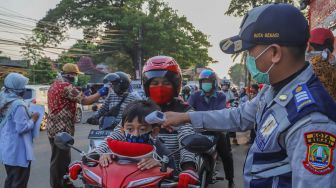 Petugas mengecek suhu tubuh pengendara sepeda motor yang akan memasuki Bekasi dengan Thermo Gun di Check Point PSBB Pondok Gede, Bekasi, Jawa Barat, Kamis (15/5). [Suara.com/Alfian Winanto]