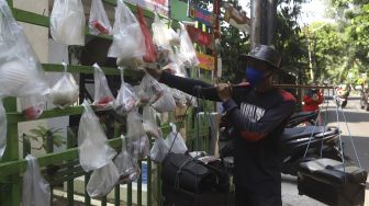 Pedagang keliling mengambil sembako yang digantung di rak kayu di kawasan Rawa Barat, Jakarta Selatan, Kamis (14/5). [Suara.com/Angga Budhiyanto]