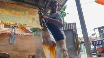 Pekerja mengaduk adonan dodol yang dimasak agar tidak mengeras di Sentra Dodol  Zakiyah, Pejaten Timur, Pasar Minggu, Jakarta Selatan, Jumat (15/5). [Suara.com/Alfian Winanto]