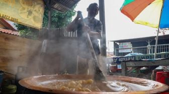 Pekerja mengaduk adonan dodol yang dimasak agar tidak mengeras di Sentra Dodol  Zakiyah, Pejaten Timur, Pasar Minggu, Jakarta Selatan, Jumat (15/5).  [Suara.com/Alfian Winanto]
