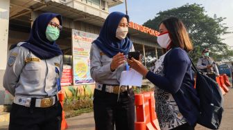 Petugas memeriksa surat tugas kantor para penumpang yang akan bekerja menggunakan transportasi Kereta Rel Listrik (KRL) di Stasiun Depok Baru, Depok, Jawa Barat, Jumat (15/5). [Suara.com/Alfian Winanto]